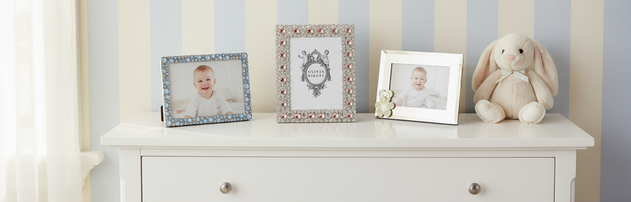 White dresser with framed baby photos and a plush bunny toy against a light gray wall.