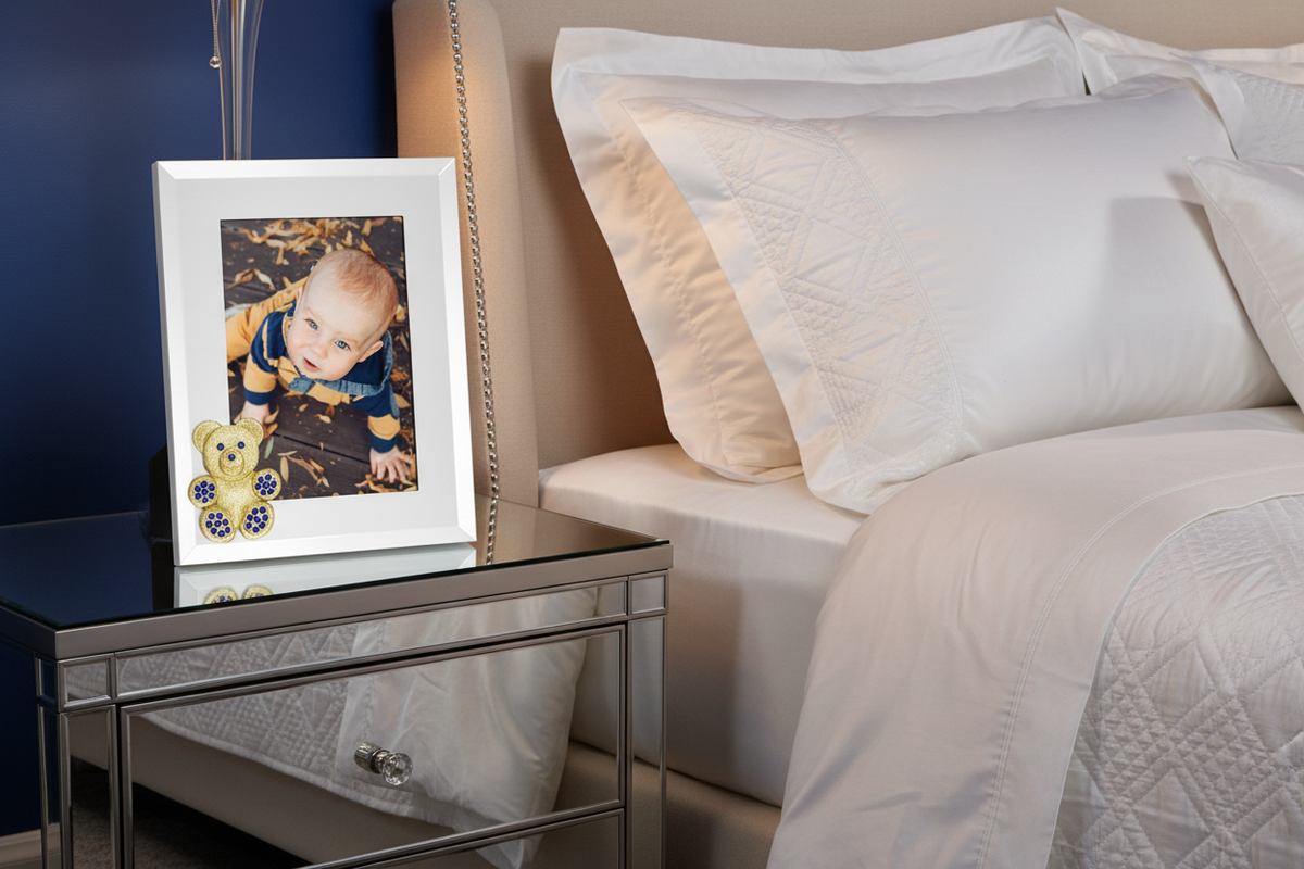 Teddy Bear frame with photo of a baby on a nightstand.