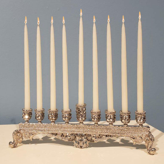Silver bejeweled menorah with white lit candles
